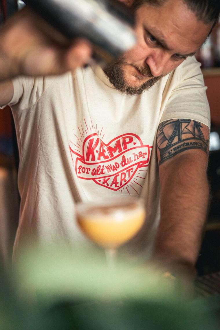 Bartender hælder op bag en cocktail i forgrunden