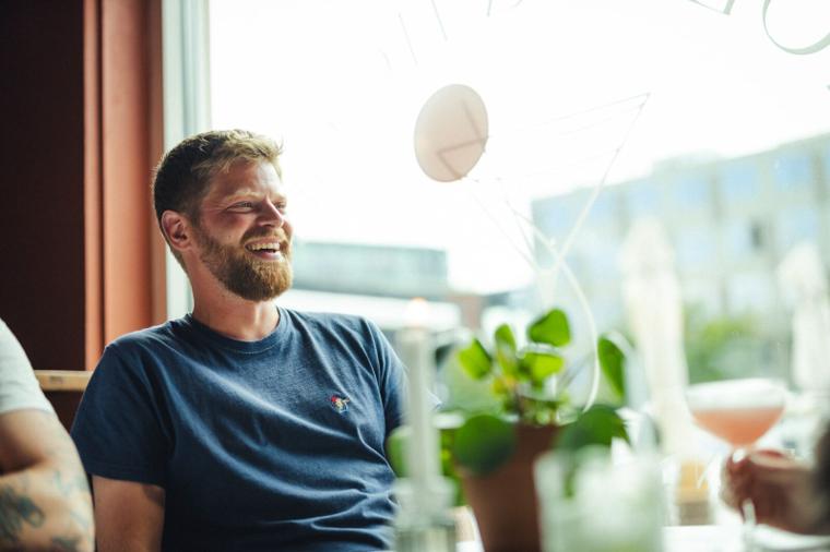 Gæst griner ved vinduet med en cocktail på karmen